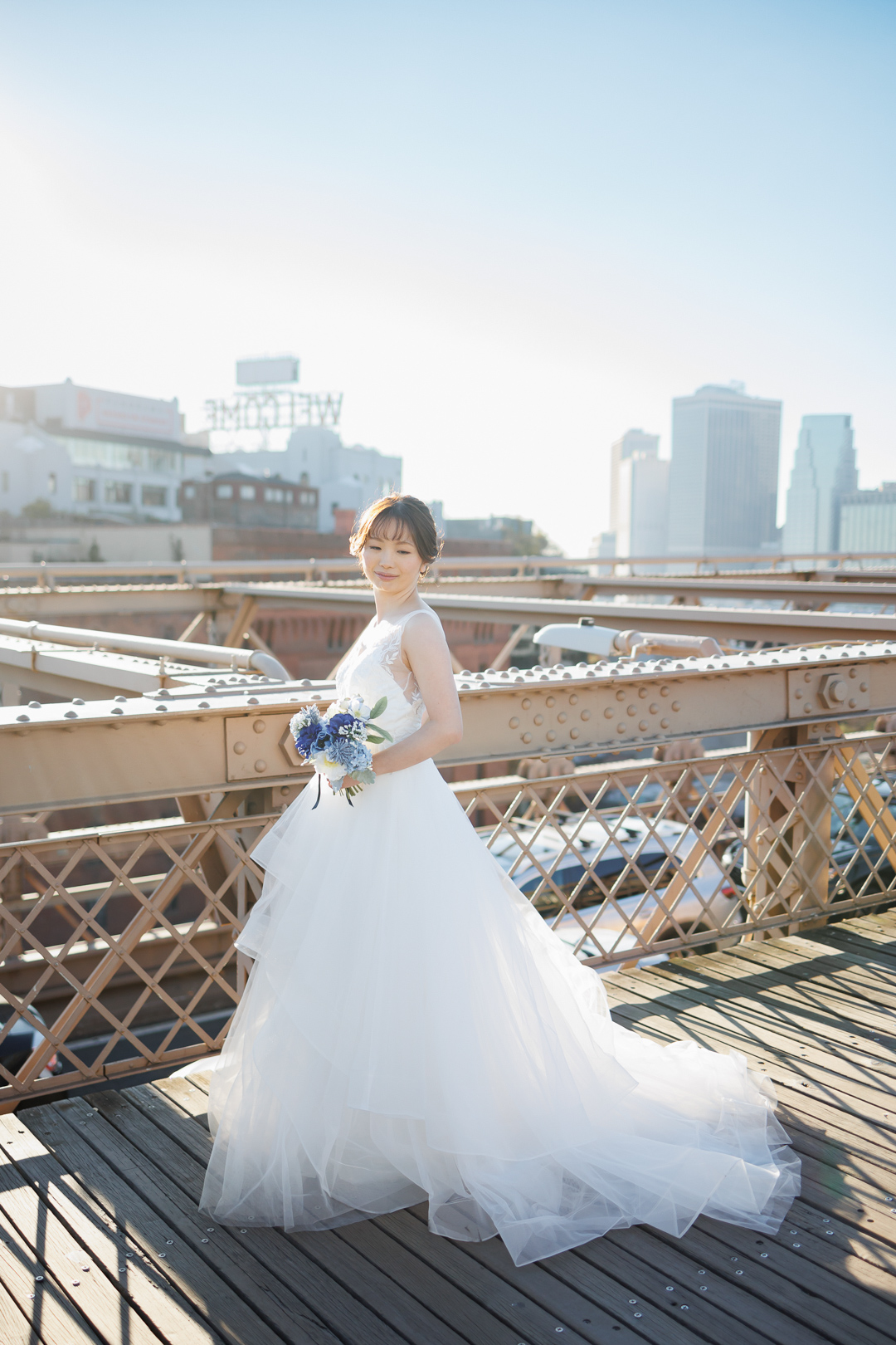 ニューヨーク前撮り/ウェディングフォト/ブルックリンブリッジに立つ美しいウェディングドレス姿の花嫁。