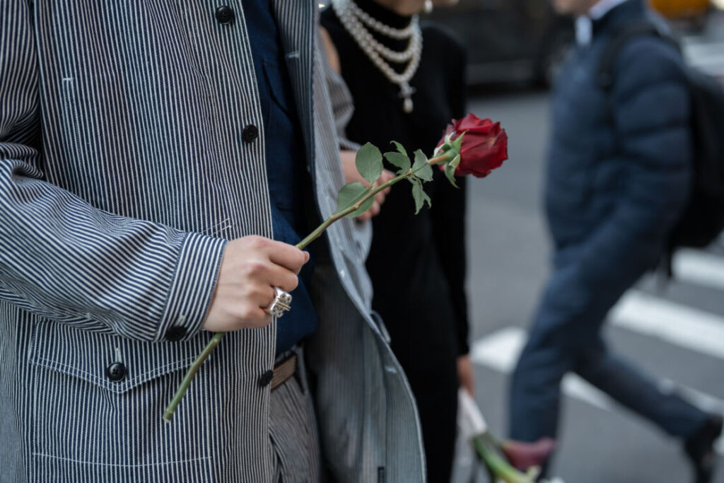 赤いバラの花一輪を持っている男性の手元