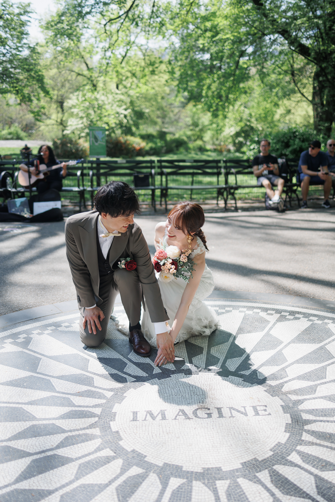 ニューヨーク前撮り/フォトウェディング|ストロベリーフィールズでモニュメントに触れる花嫁と花婿。