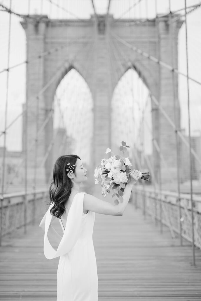 ニューヨークの前撮り/フォトウェディング|ブルックリンブリッジでブーケを掲げる花嫁。