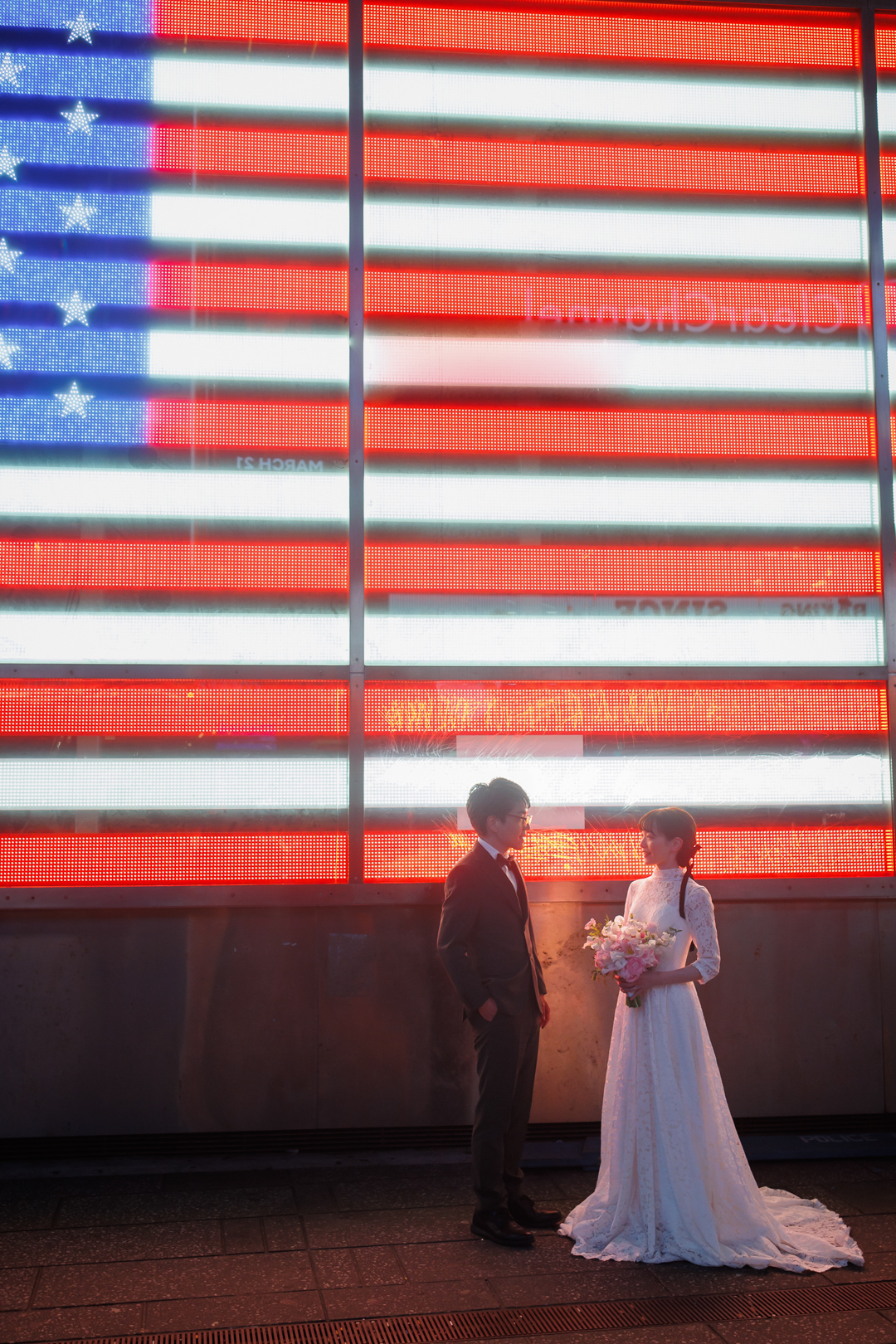 アメリカニューヨークの前撮り/フォトウェディング/アメリカ国旗のネオンサインの前に立つ花嫁花婿。