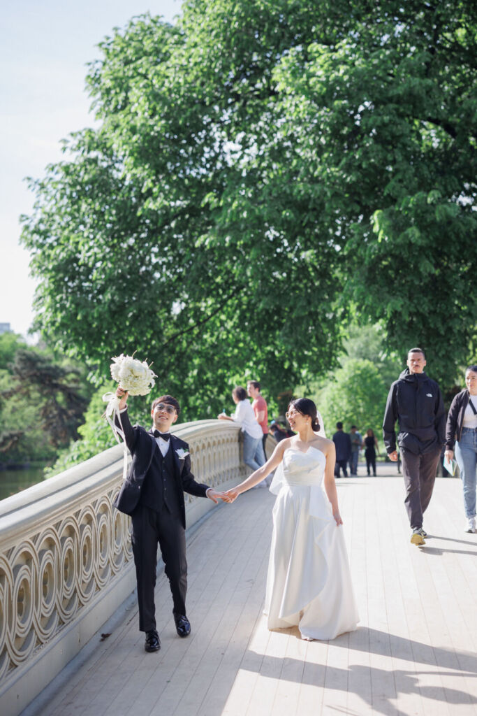 ニューヨークの前撮り/ウェディングフォト|ボウブリッジに立つサングラスをした花婿と花嫁。