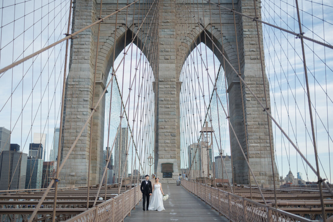 ニューヨークの前撮り/ウェディングフォト|ブルックリンブリッジを手をつないで歩く花嫁と花婿。