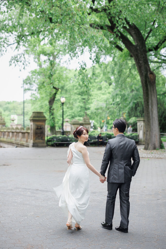 ニューヨーク前撮り/ウェディングフォト|セントラルパークを手をつないで歩くカップルのバックショット。