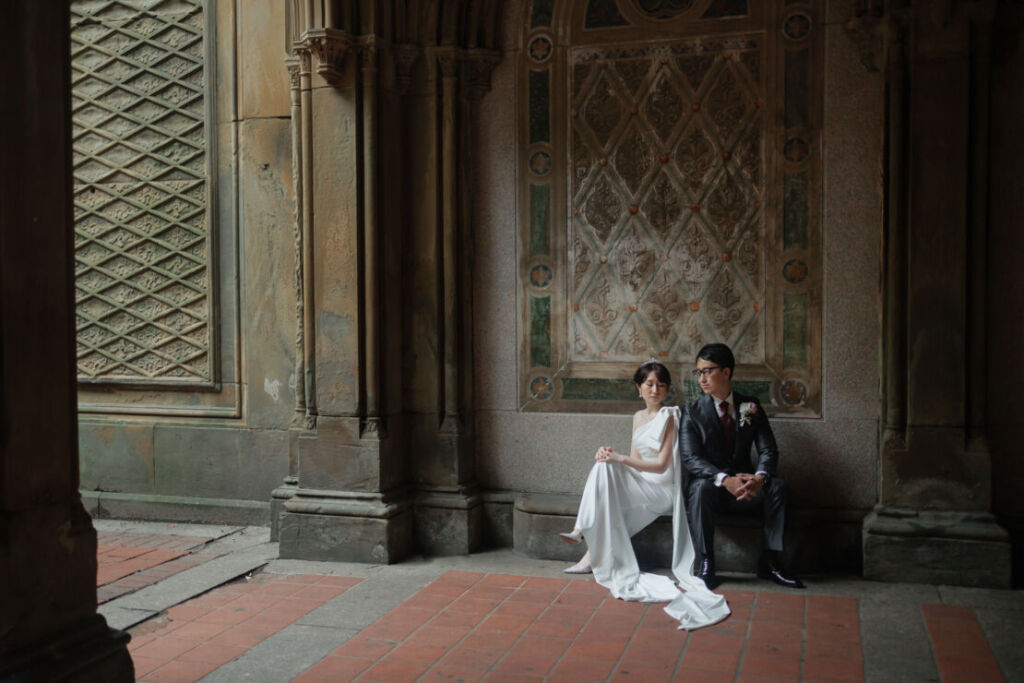 ニューヨーク前撮り/ウェディングフォト|壁画の前で腰をおろす花嫁と花婿。