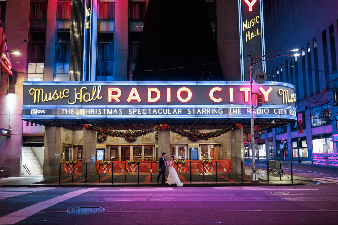 ニューヨークの前撮り/ウェディングフォト|RADIO CITY MUSIC HALL前に立つカップル。