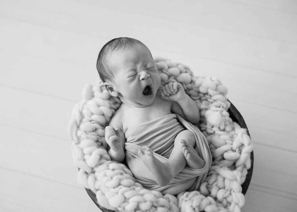 ニューヨークでニューボーンフォト/バスケットの中であくびをする新生児。