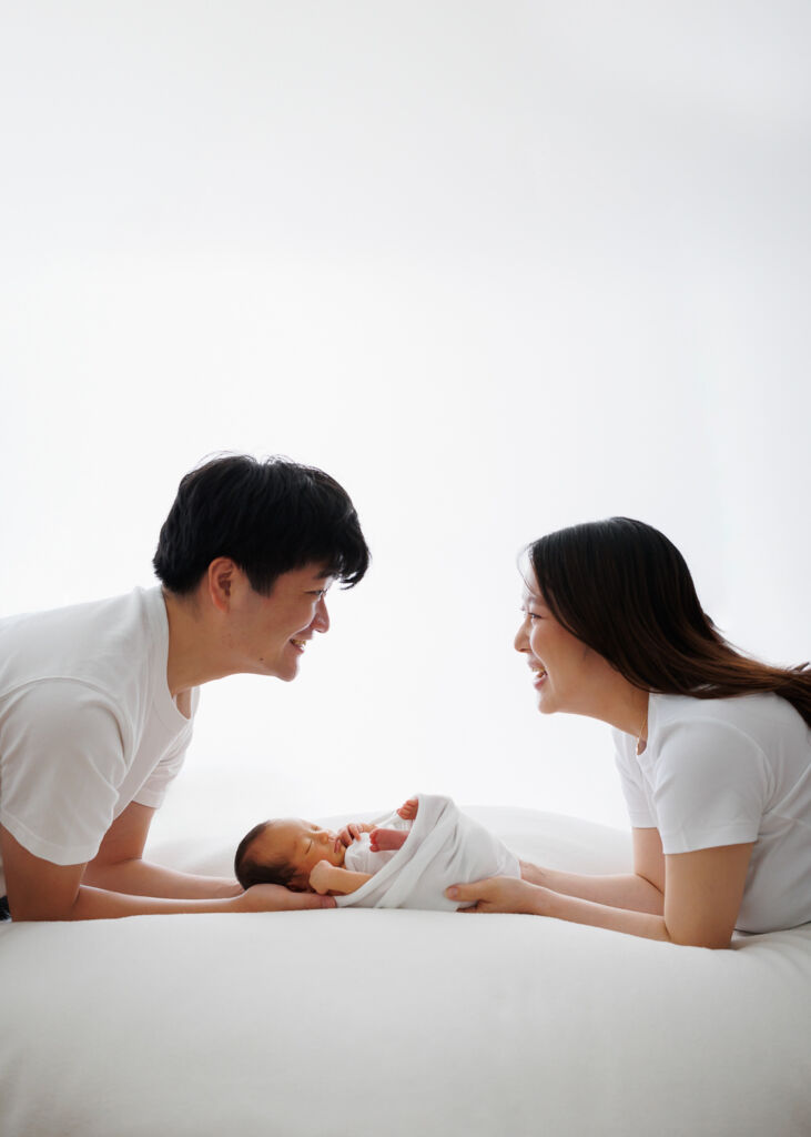 ニューヨークのニューボーンフォト/新生児を間にして、向かい合うパパとママ。
