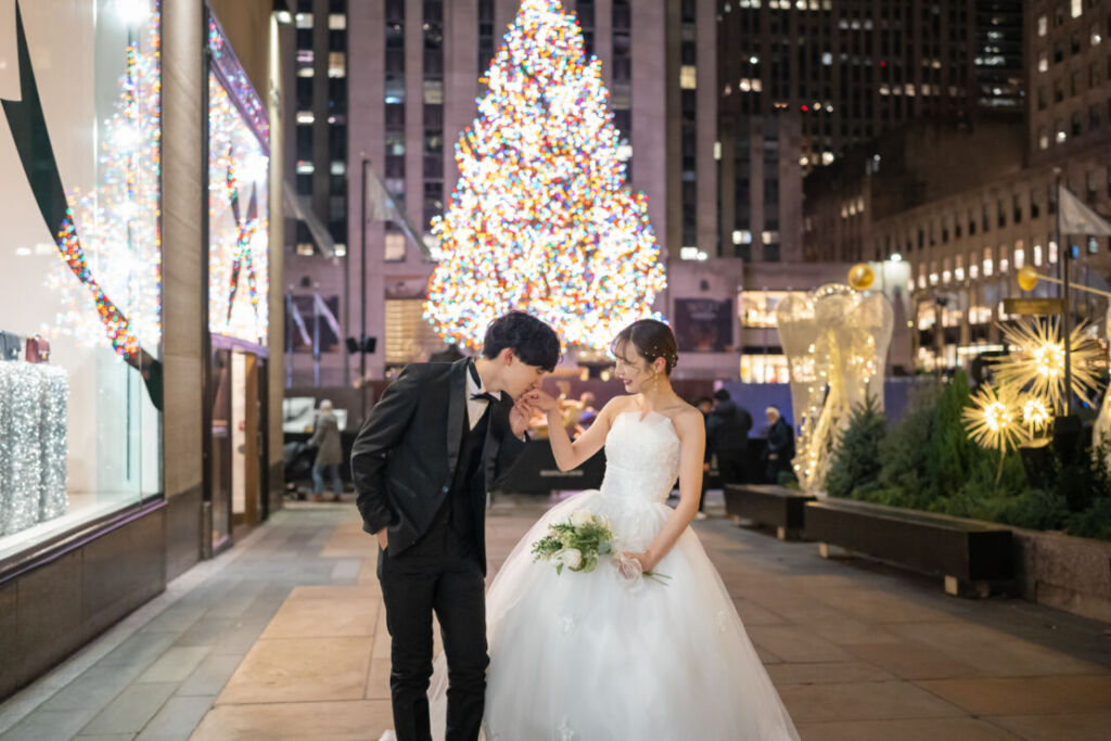 ニューヨークの前撮り|フォトウェディング/ロックフェラーセンターのクリスマスツリーの前に立つ花嫁と花婿。