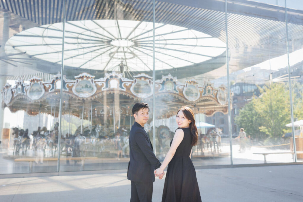 ニューヨークの前撮りウェディングフォト/Jane`sCarouselのガラス張りに黒いドレスが引き立っている。