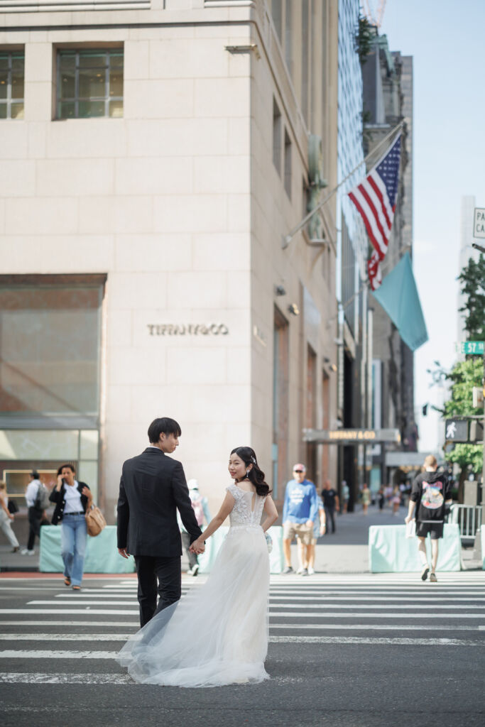 ニューヨークのウェディングフォト/前撮り|５番街を手をつないで歩く花嫁と花婿。