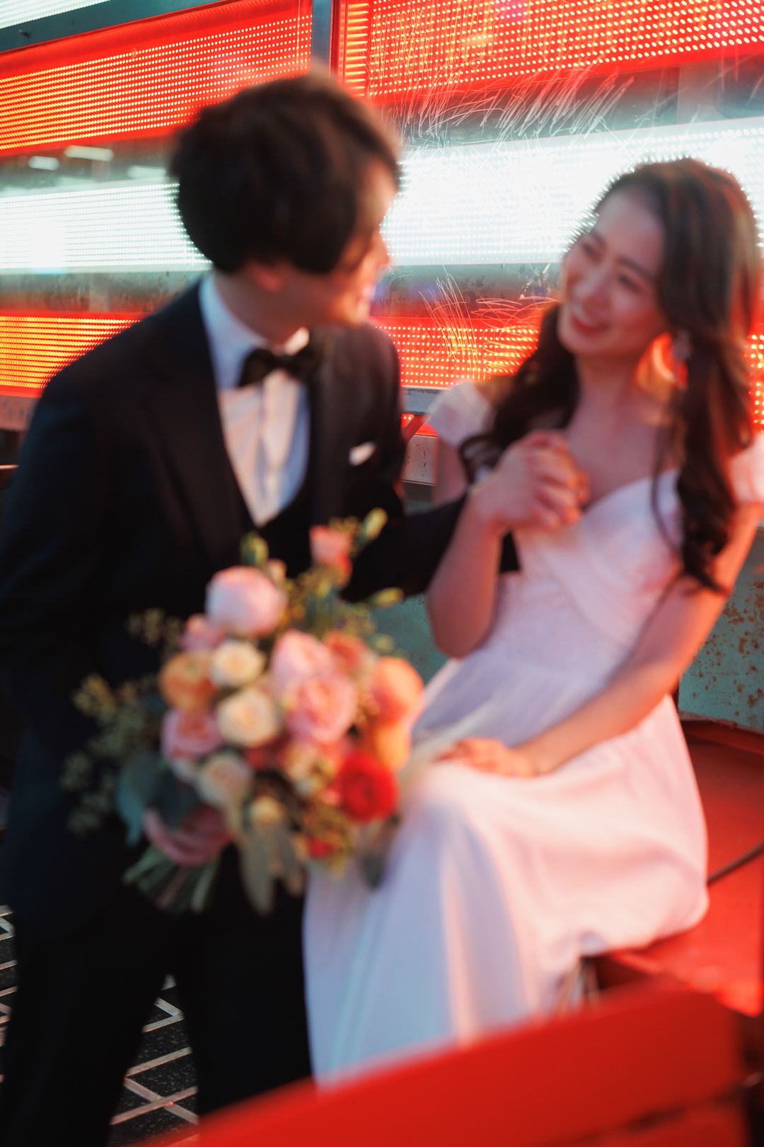 ニューヨークのウェディングフォト/前撮り|アメリカ国旗のネオン前に座る花嫁と花婿。