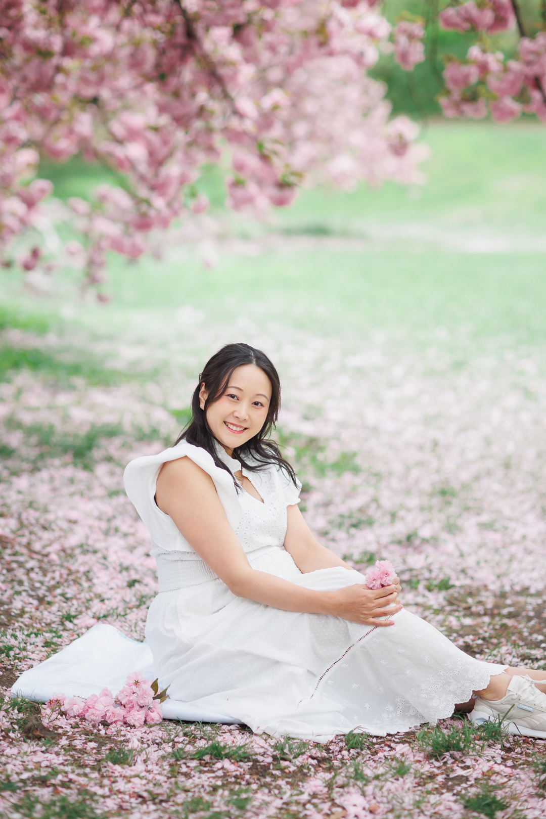 ニューヨークのマタニティフォト|妊婦さんが桜の絨毯の上に座っている。
