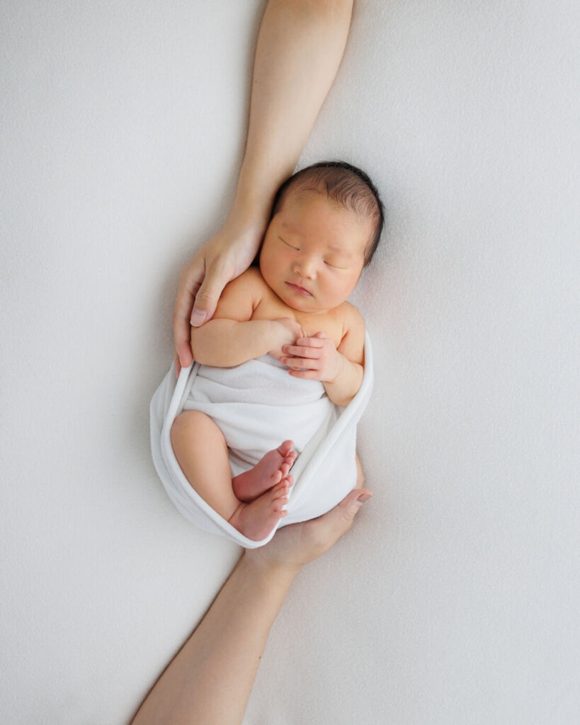 ニューヨークでニューボーンフォト/パパとママの手に包まれるベビちゃん。