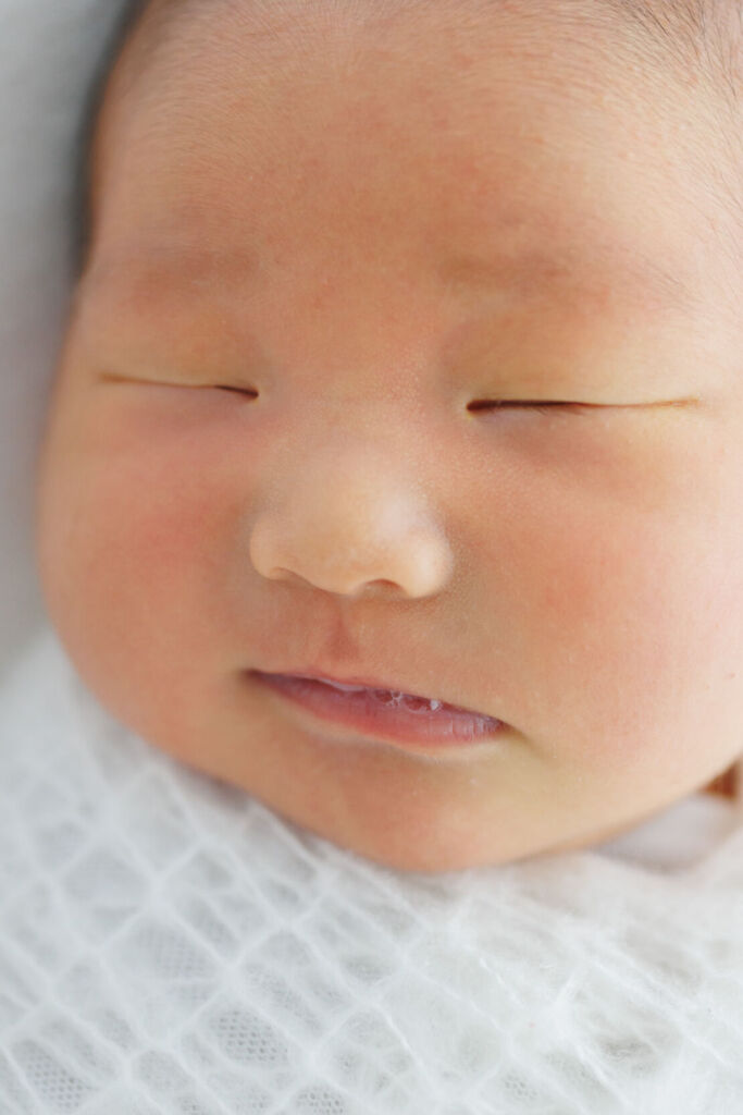 ニューヨークでニューボーンフォト/みのむしポーズの新生児のあどけない顔。