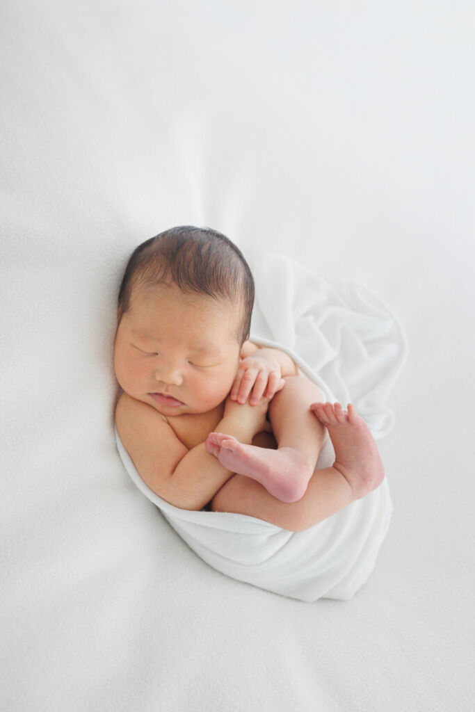 ニューヨークでニューボーンフォト/おくるみに包まれて気持ちよさそうな新生児。