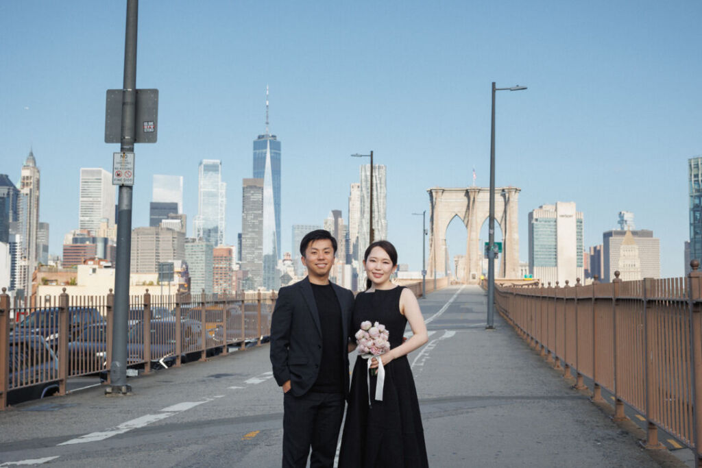 ニューヨークの前撮りウェディングフォト/ブルックリンブリッジの上に立つ花嫁と花婿。