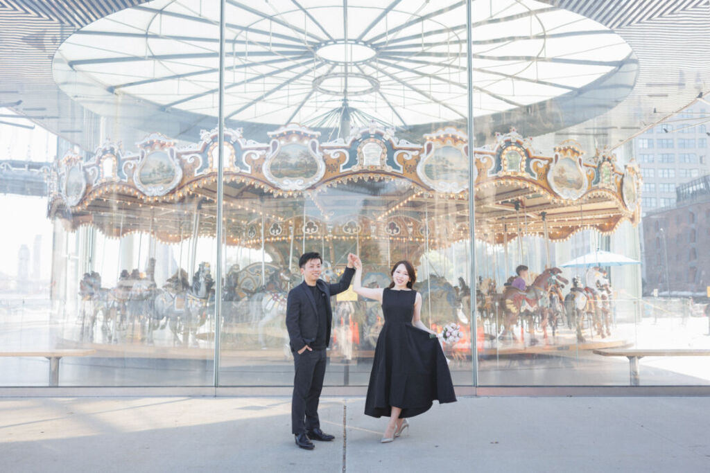 ニューヨークの前撮りウェディングフォト/Jane`s Carouselの前で踊る花嫁と花婿。
