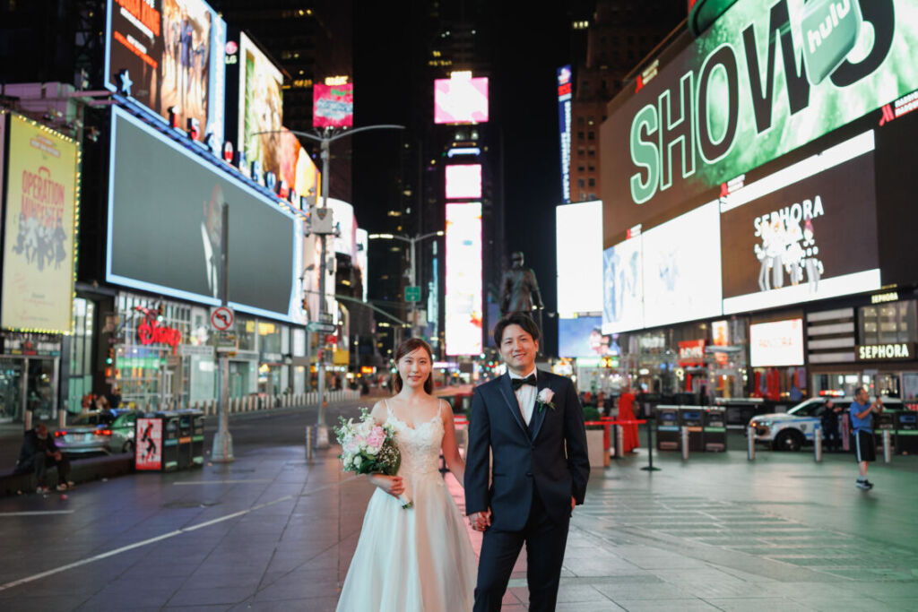 ニューヨークのウェディングフォト|前撮り/タイムズスクエアの広場に立つ花嫁と花婿。