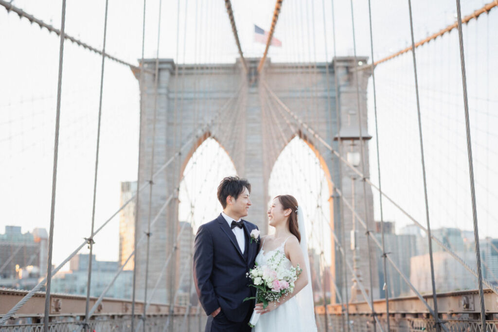 ニューヨークのウェディングフォト|前撮り/ブルックリンブリッジで笑い合う花嫁と花婿。