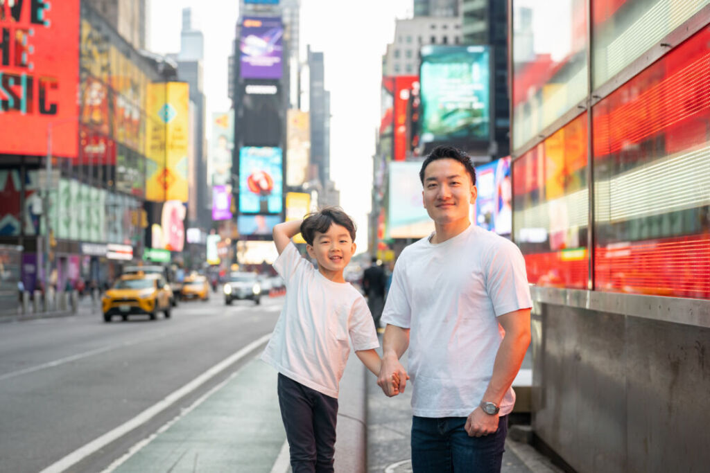 ニューヨークでファミリーフォト/タイムズスクエアで手をつなぐパパと男の子。