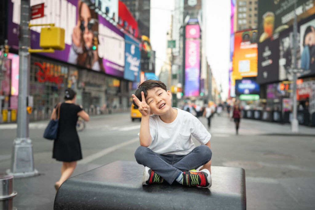ニューヨークでファミリーフォト/タイムズスクエアでピースサインをする男の子。