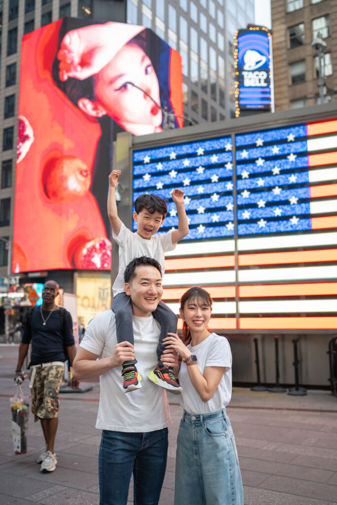 ニューヨークでファミリーフォト/タイムズスクエアのネオンの前で肩車される男の子。