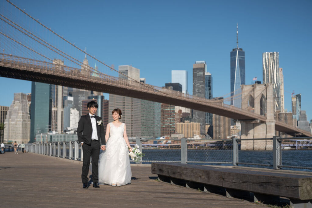 ニューヨークの前撮り|ウェディングフォト/ブルックリンブリッジパークを手をつないで歩くご夫婦。