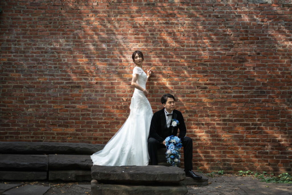ニューヨークの前撮り|ウェディングフォト/レンガの壁の前で絵画のようなカップルのお姿。