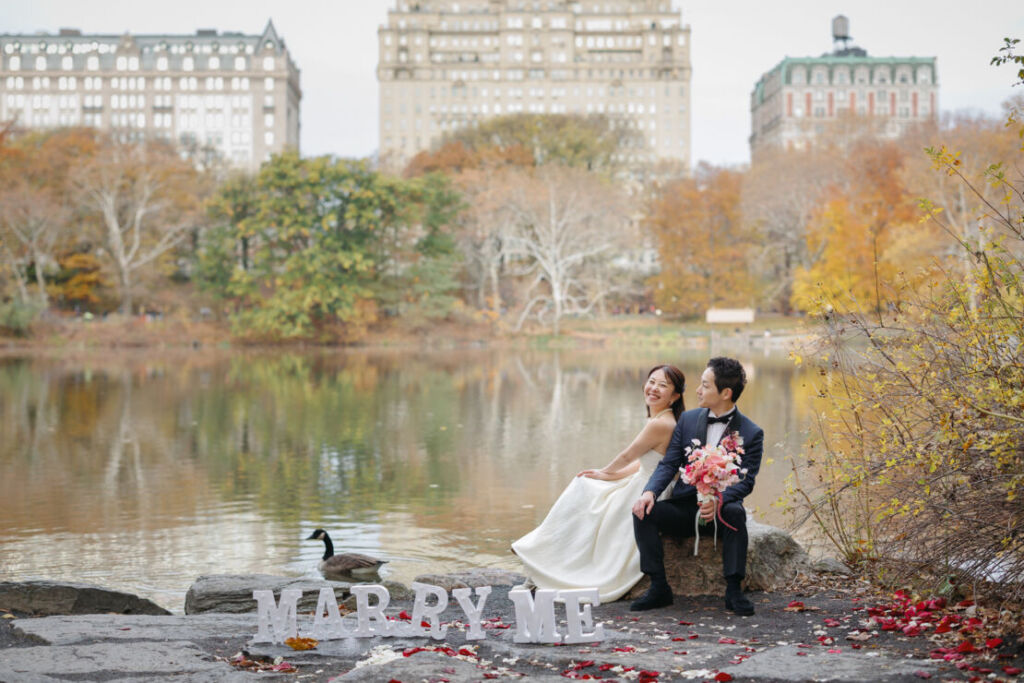 ニューヨークの前撮り|ウェディングフォト/MarryMeという看板が湖のほとりにおいてある。