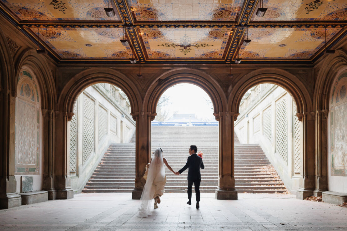 ニューヨークの前撮り|ウェディングフォト/ベセスダテラスのアーケードを走る花嫁と花婿。
