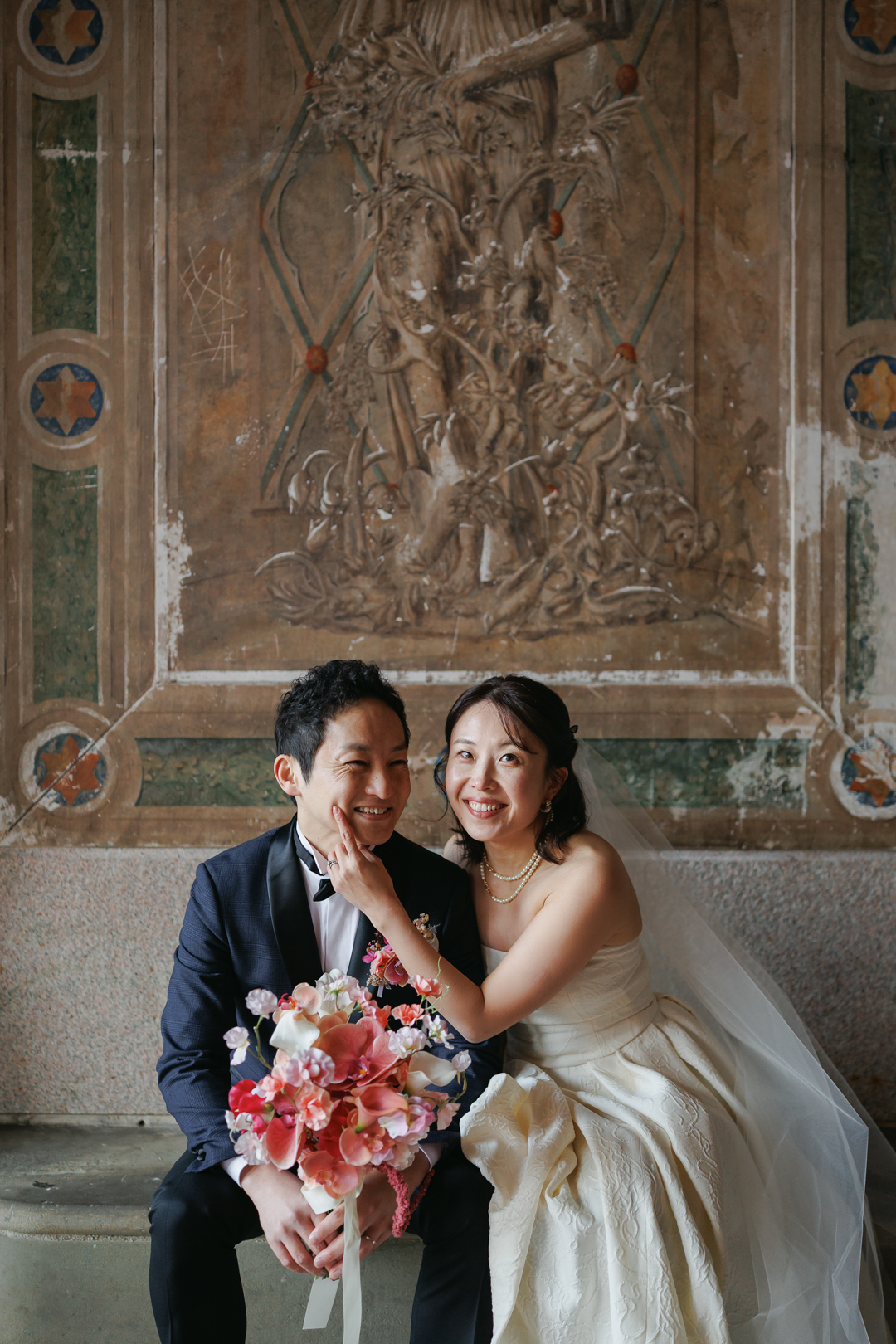 ニューヨークの前撮り|ウェディングフォト/ベセスダテラスの壁画前に座る花嫁と花婿。