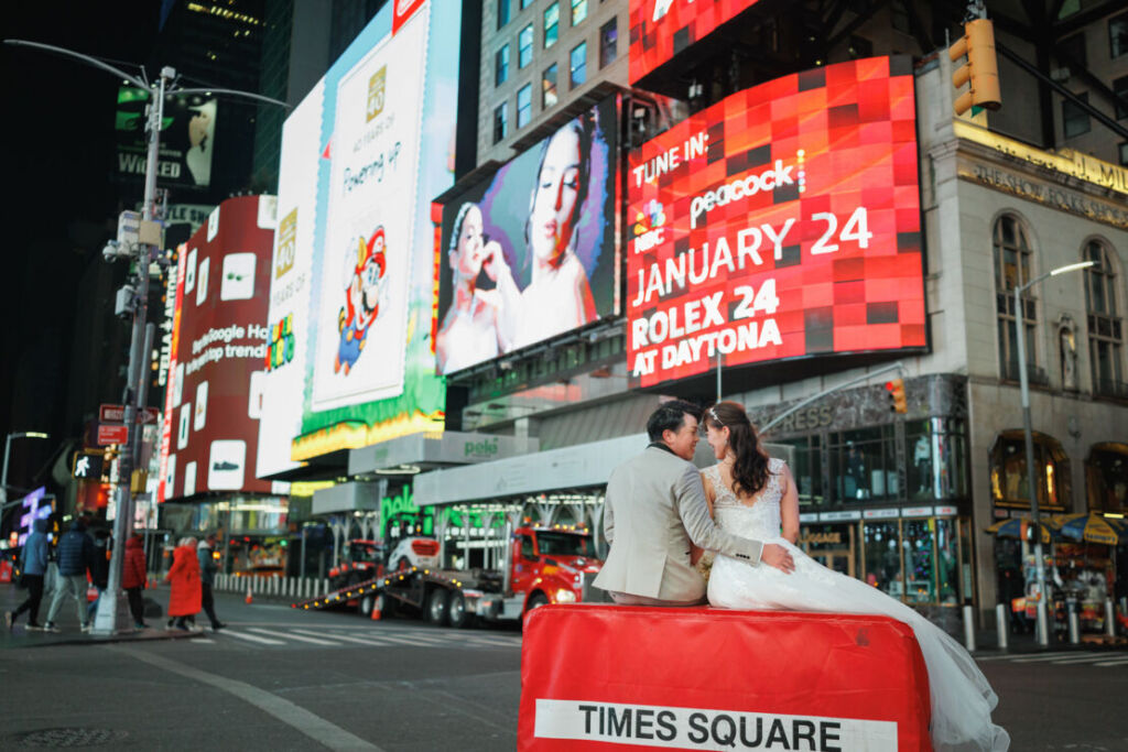 ニューヨークの前撮り|ウェディングフォト/タイムズスクエアに腰を掛けるお二人。