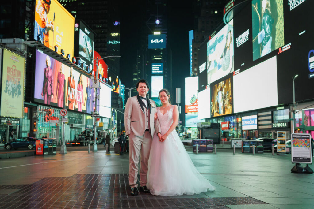 ニューヨークの前撮り|ウェディングフォト/広場でネオンサインに囲まれる花嫁と花婿。