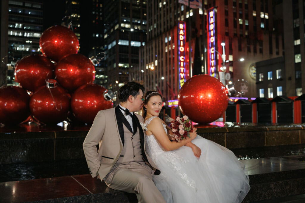 ニューヨークの前撮り|ウェディングフォト/ラジオシティホールのクリスマスオーナマントとカップル。