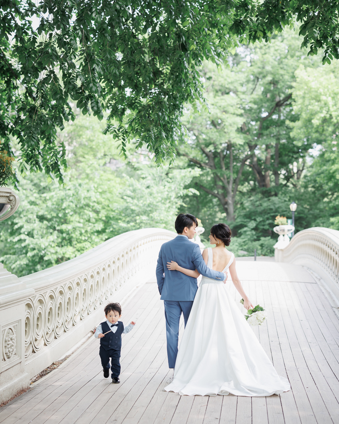 ニューヨークでフォトウェディング|前撮り/ウェディング姿のパパとママの隣を息子君が走る。